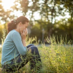 Woman with allergies sitting amidst ragweed pollen