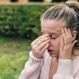 Woman with severe allergies holding her nose and head