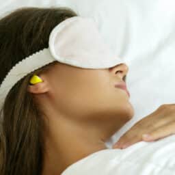 Woman sleeping with earplugs and an eye mask.